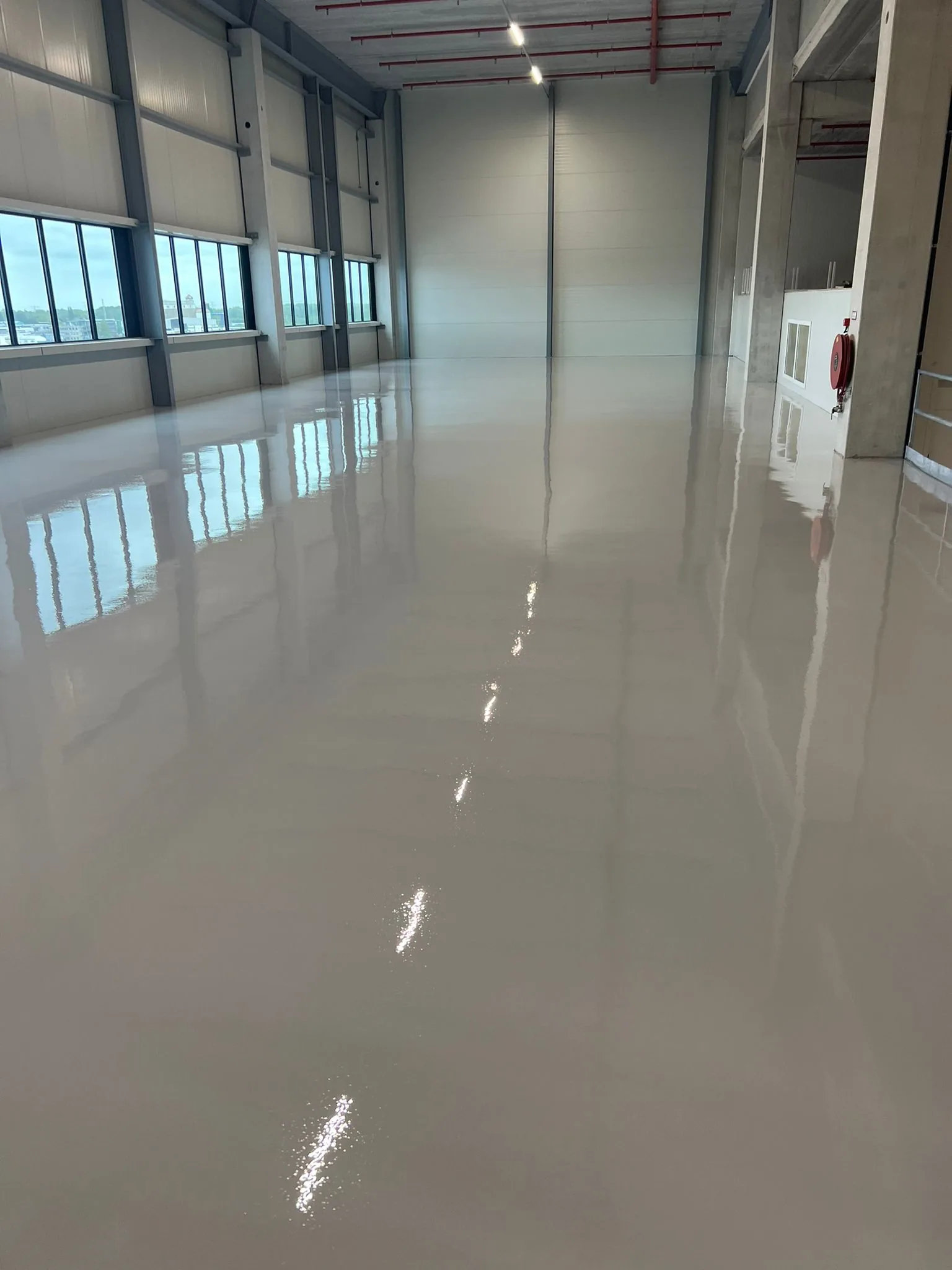 Spiegelend gladde Comforpox 800 SL epoxy gietvloer in een lege productiehal