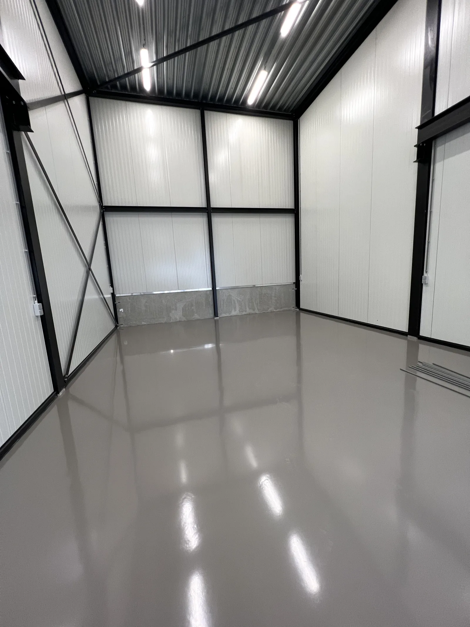 Antracietgrijze epoxy gietvloer in een nieuw bijgebouw met witte wandpanelen