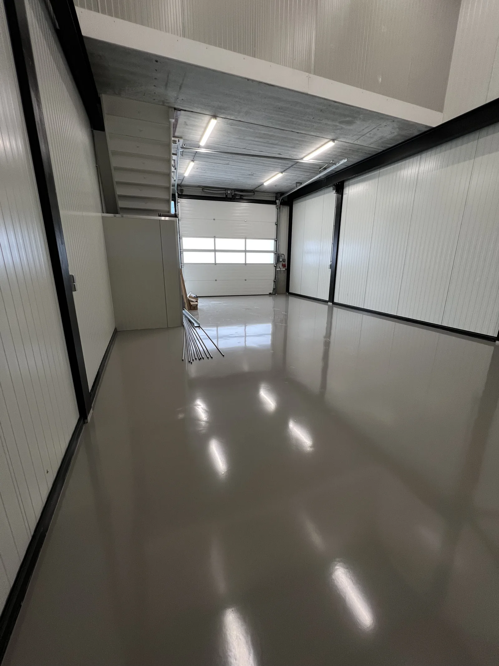 Spiegelende grijze epoxy gietvloer in een garage met overheaddeur