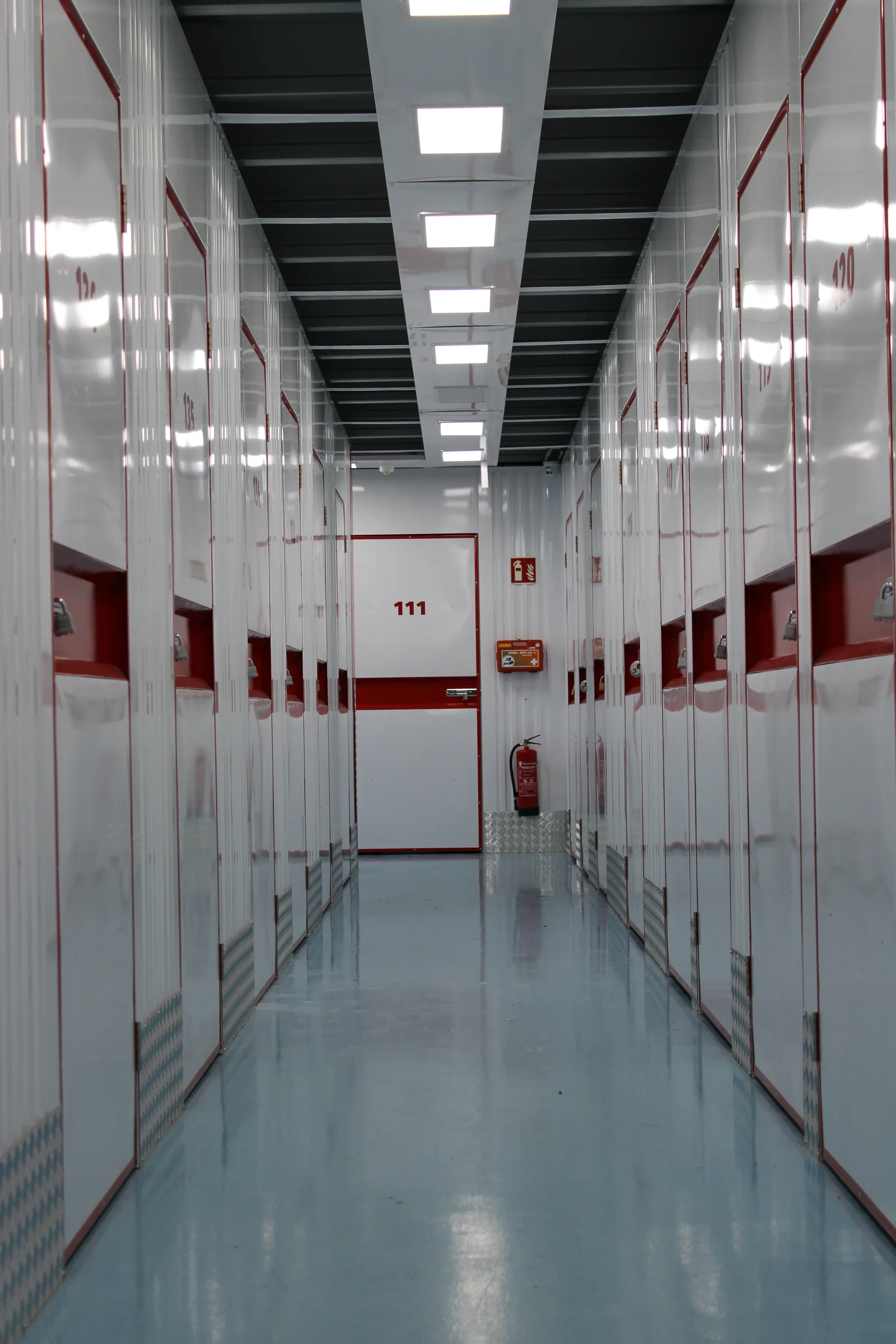 Witte epoxy coating in een gang met rode opslagboxen van een self-storage