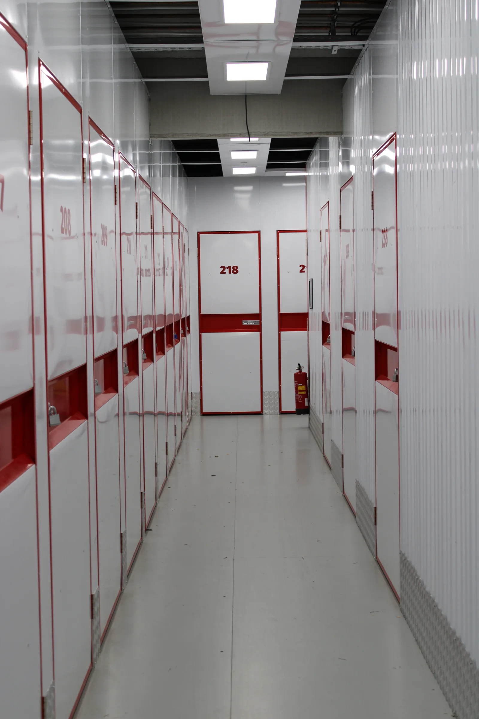 Lichte epoxy vloercoating in een self-storage met genummerde rode deuren
