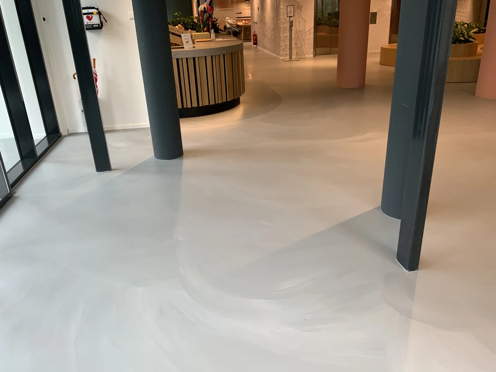 Betonlook gietvloer in een bedrijfsrestaurant met bar en zithoeken