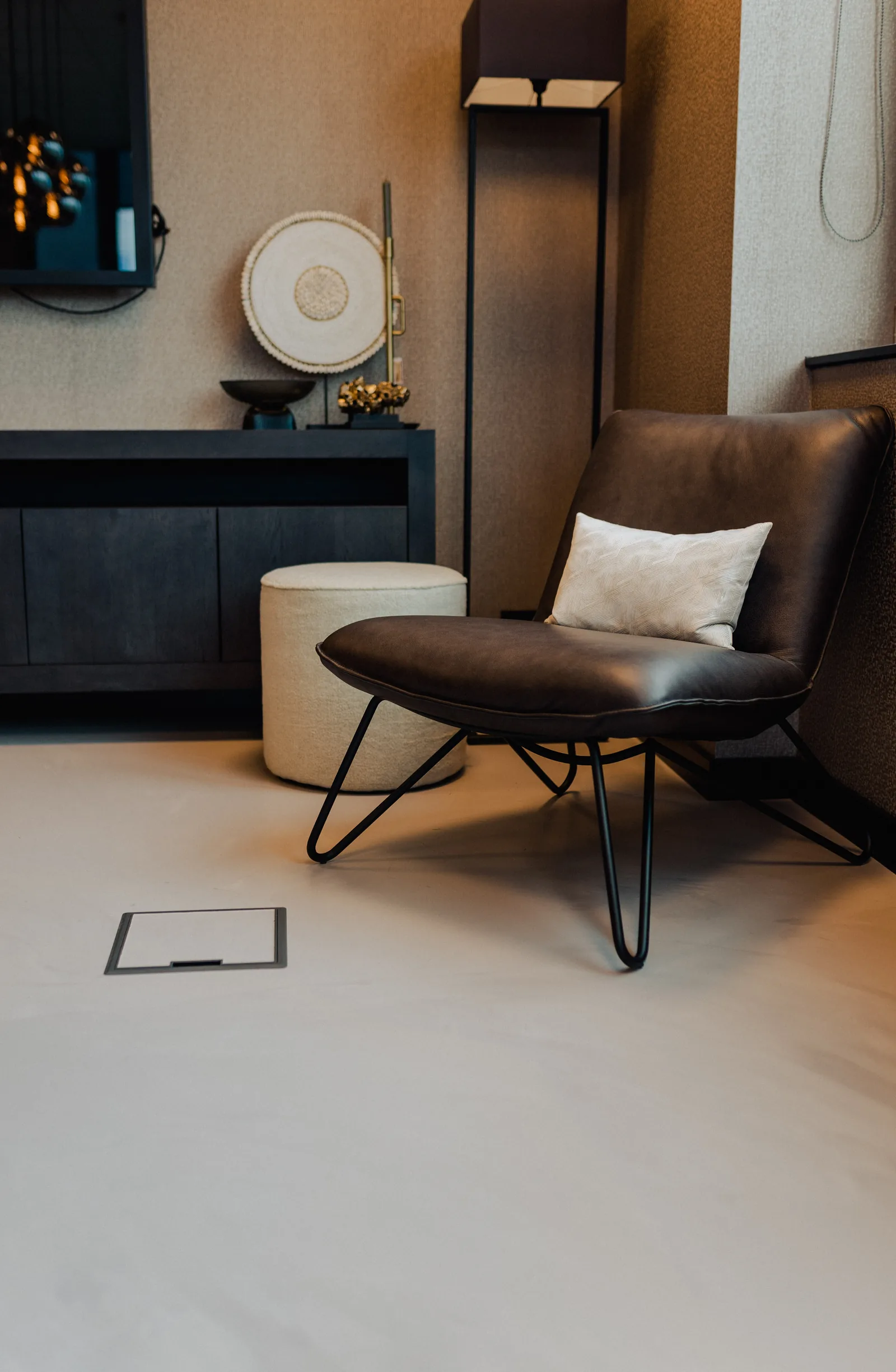 Lichte gietvloer in een showroom onder een leren fauteuil en poef