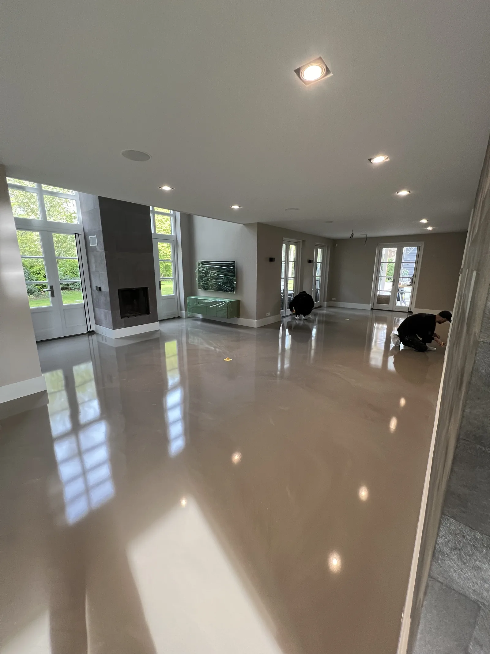 Hoogglans Comforpur 690 Greenline gietvloer in een woonkamer met openslaande deuren naar de tuin