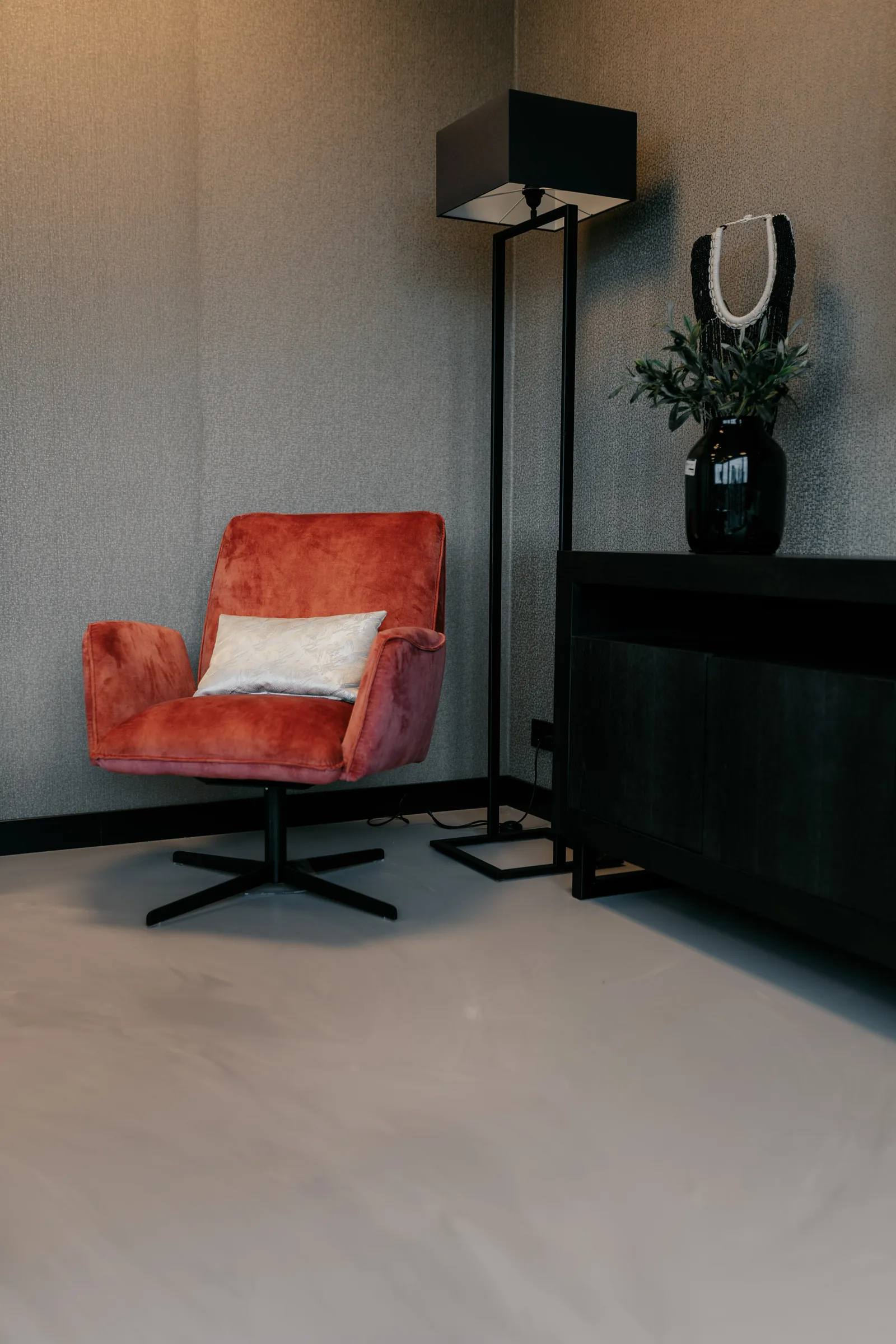 Gietvloer in een zithoek met rode velours fauteuil en zwart dressoir