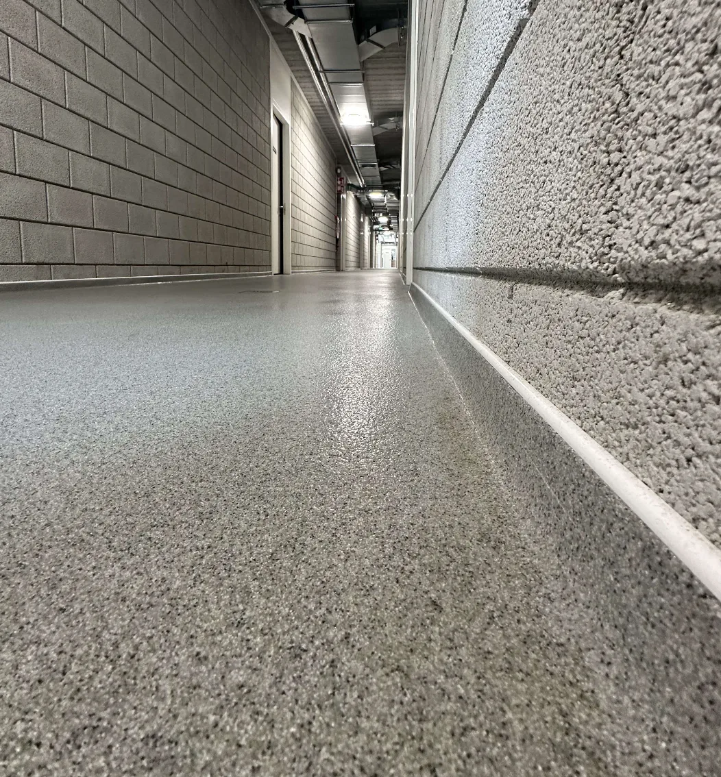 Detail van een holle plint in QCF kwartsvloer langs een gemetselde wand