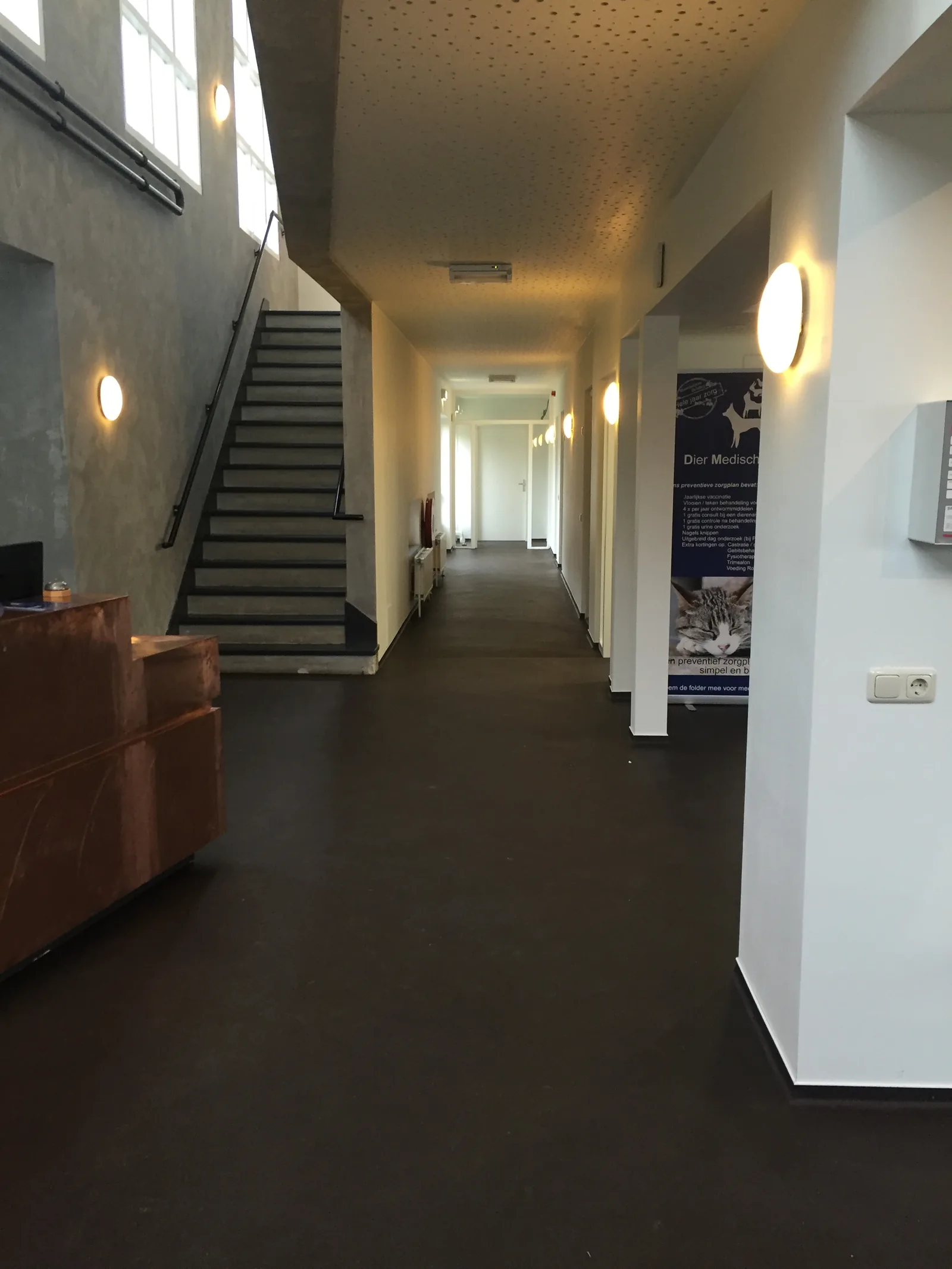 Antracietgrijze kwartsvloer in een hotelgang met trap en zithoek
