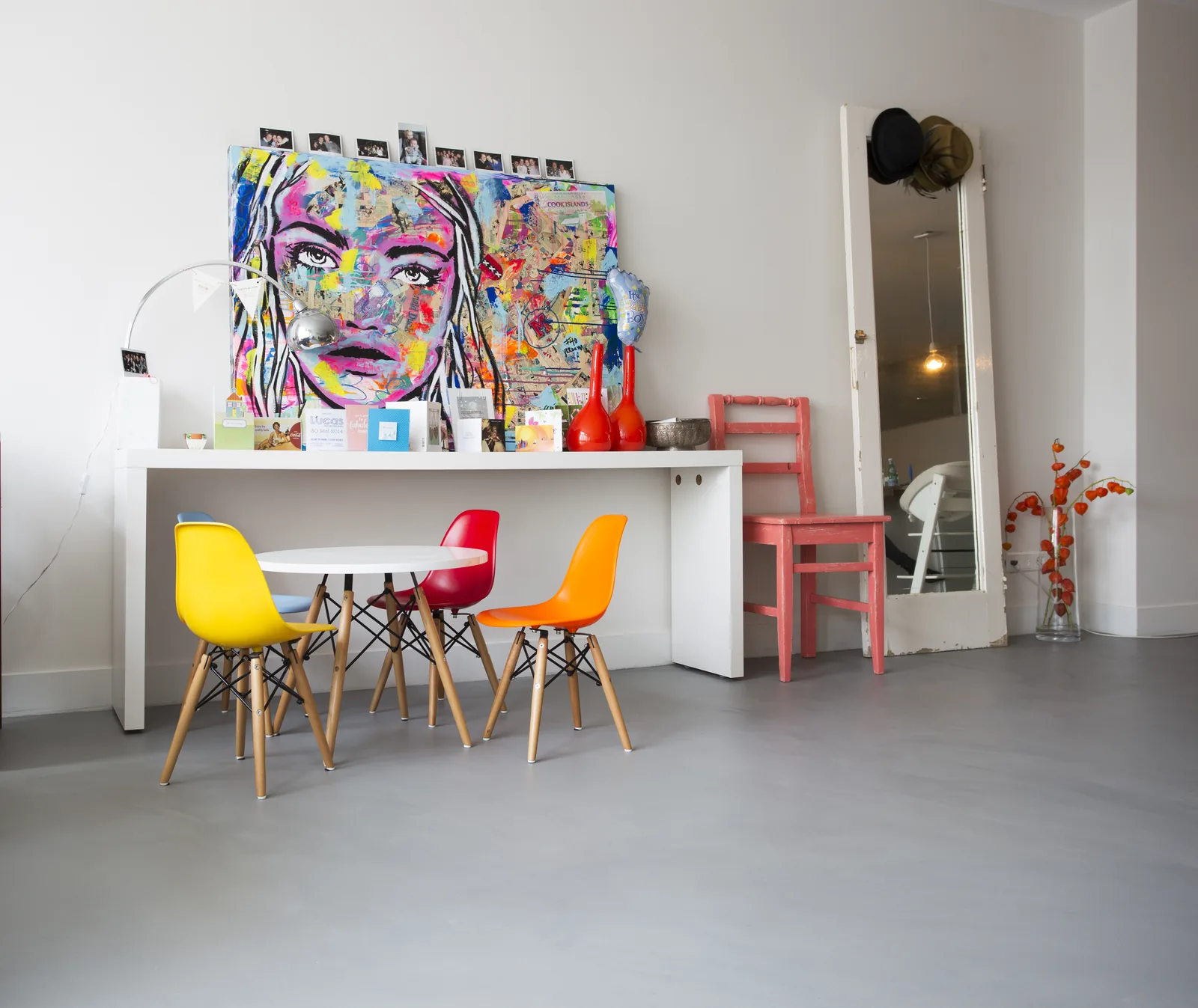 Gietvloer in een eethoek met gekleurde stoelen en kunst aan de wand