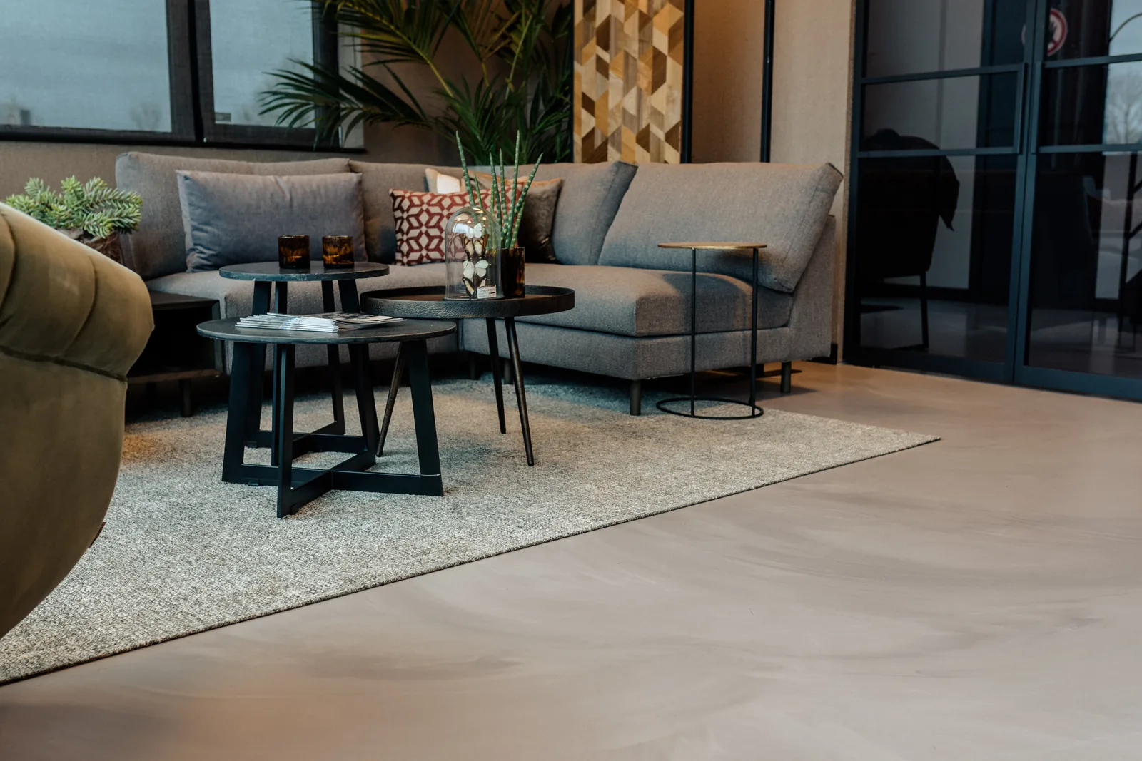 Corestone Nature gietvloer in een woonkamer met grijze hoekbank en vloerkleed