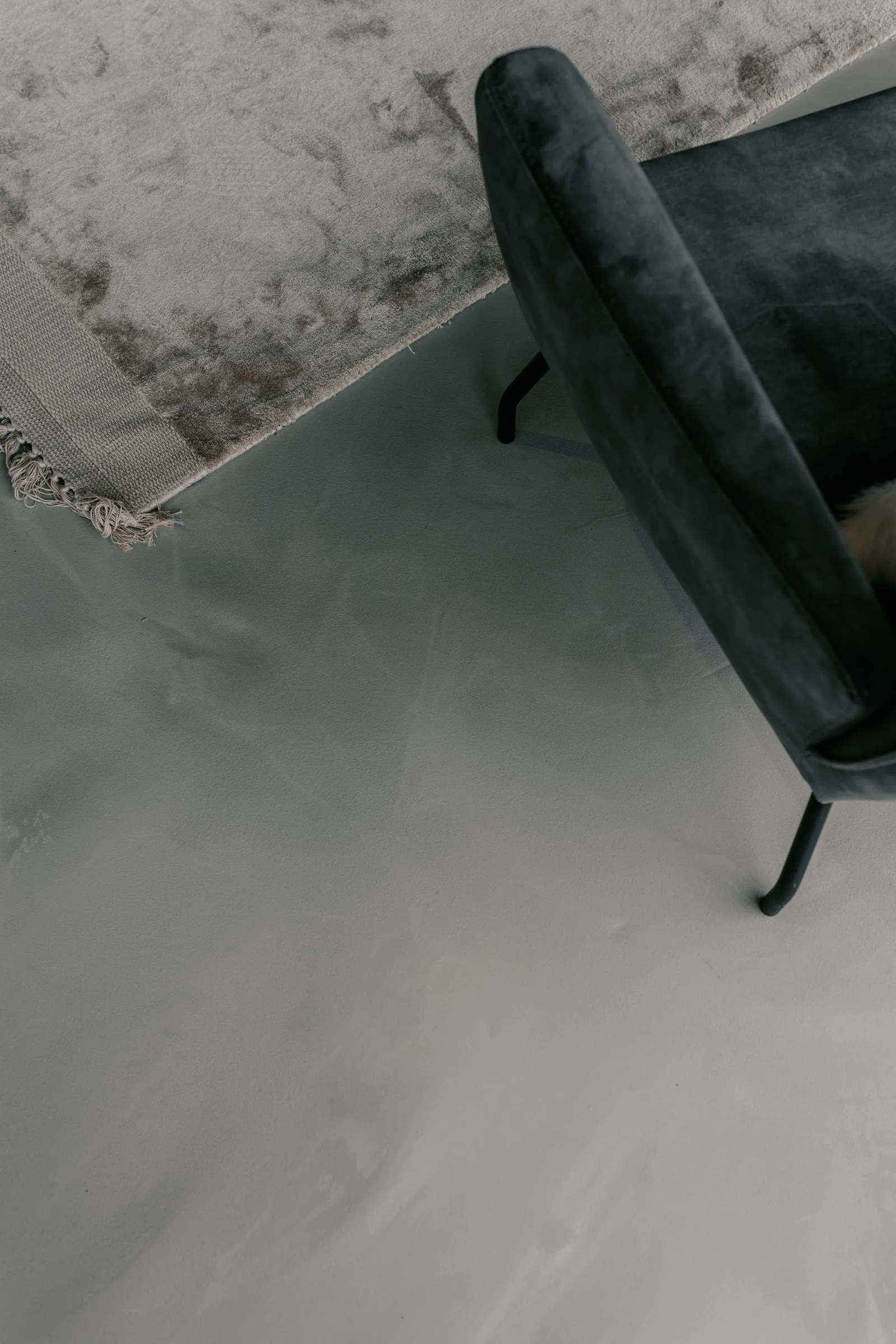 Corestone Nature gietvloer in een showroom met grijze fauteuil en vloerkleed