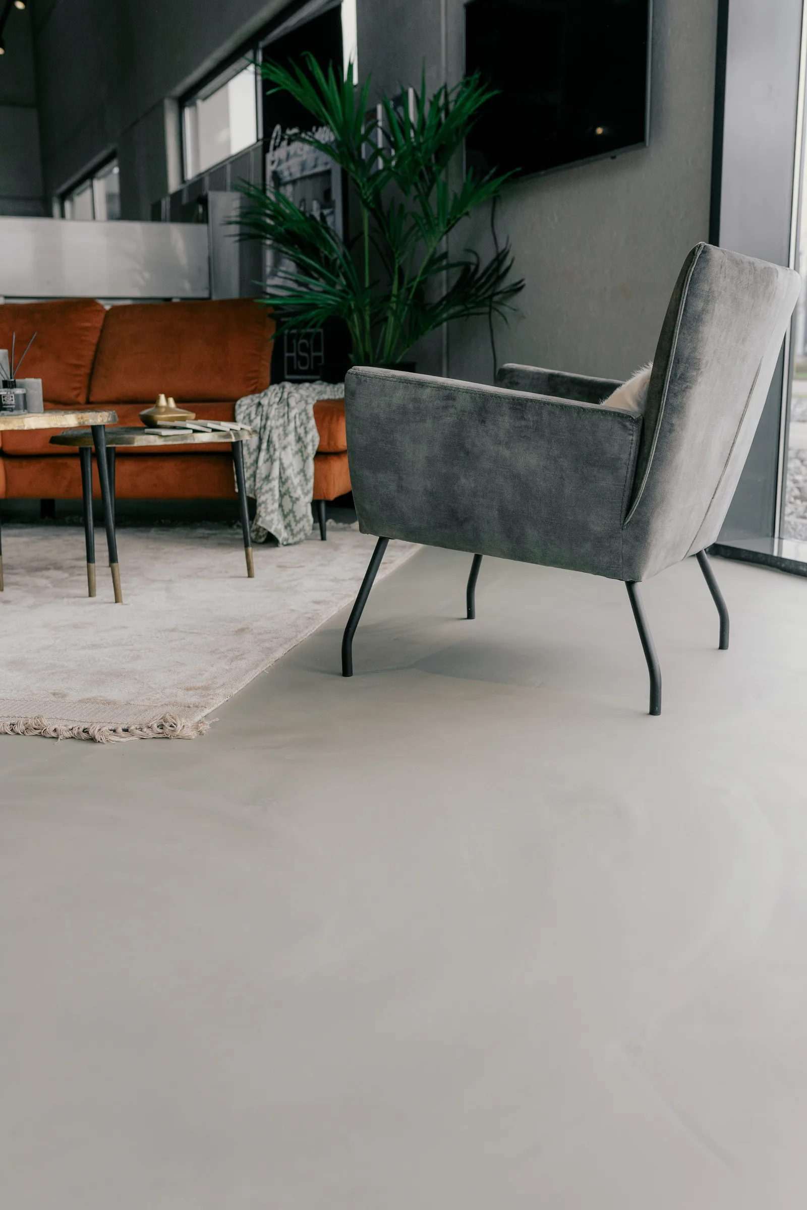 Corestone Nature gietvloer in een zithoek met oranje bank en fauteuil