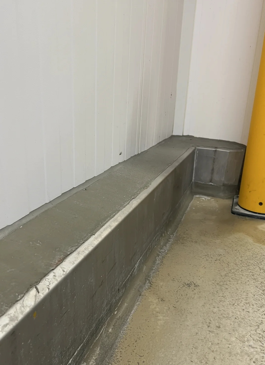 Detail VA-B: RVS aanrijdbeveiliging op maat, gevuld met beton en afgewerkt met het vloersysteem