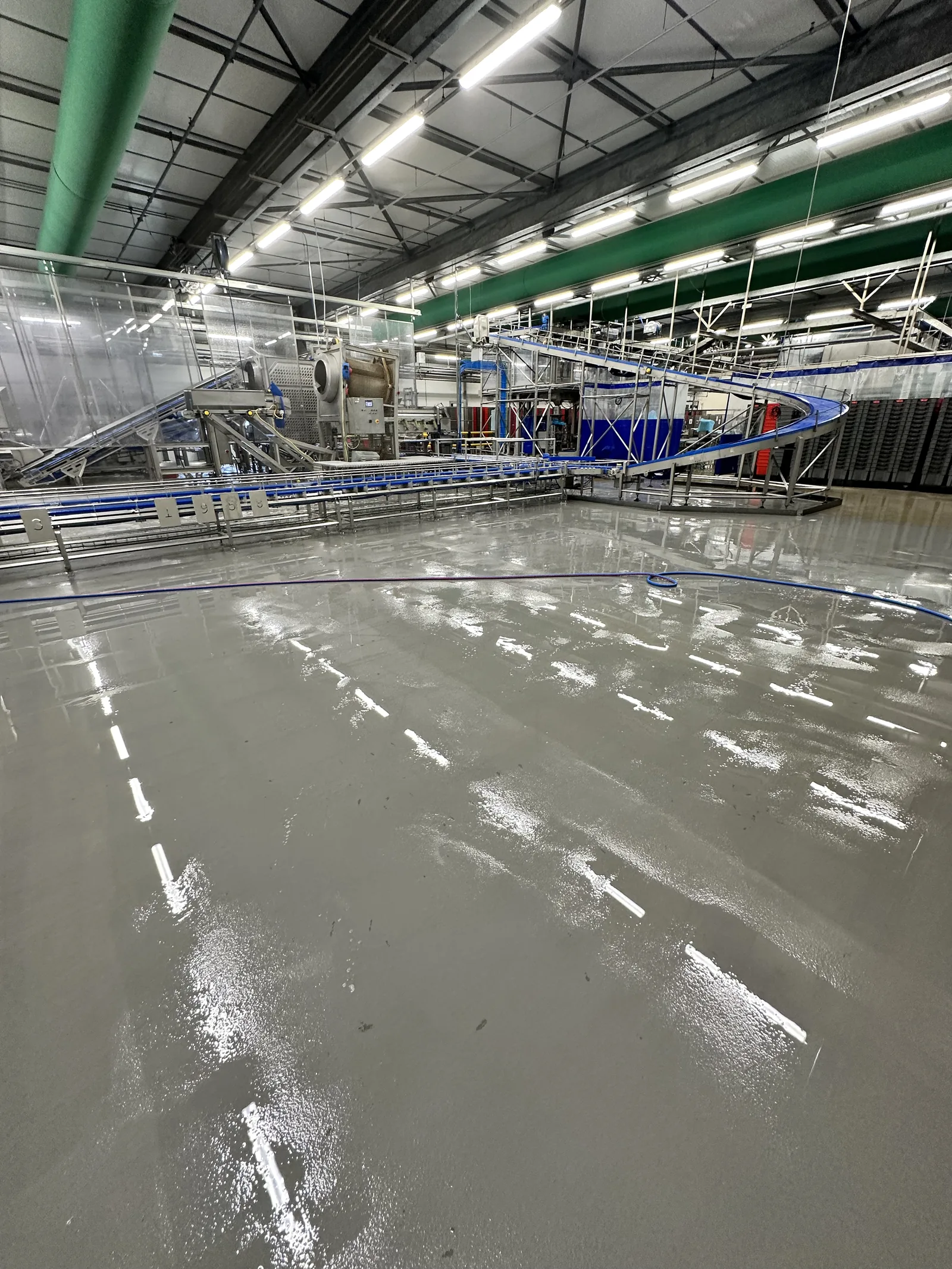 Natte Ucrete vloer met witte belijning in een verwerkingshal