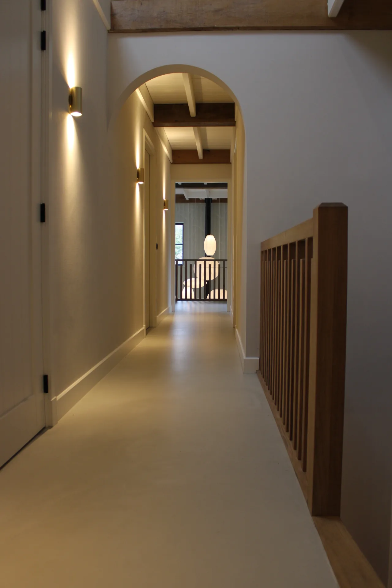 Lichte gietvloer op een overloop met houten trap en balustrade