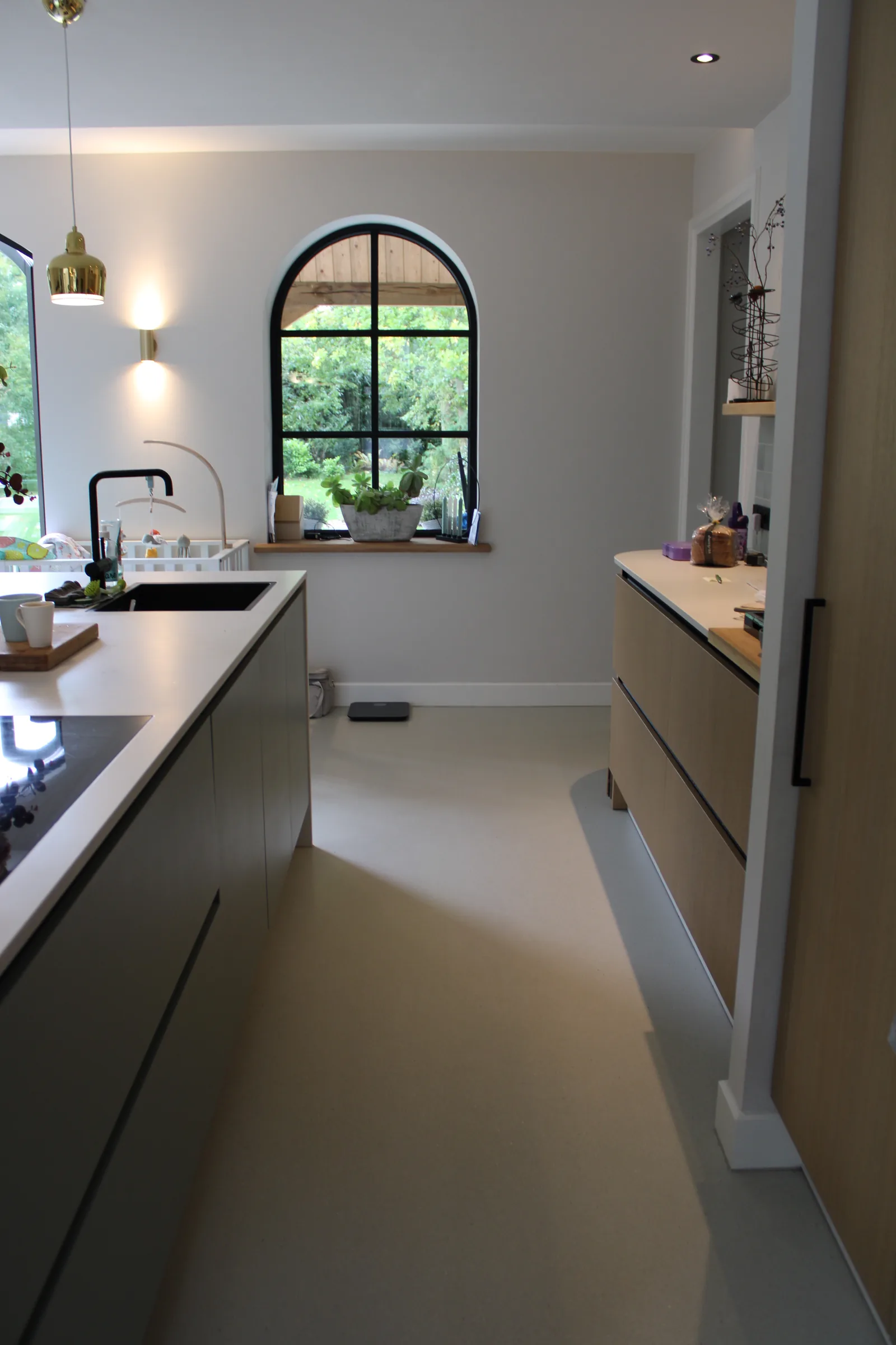 Superbase Classic gietvloer in een woonkeuken met houten kasten en boogvenster