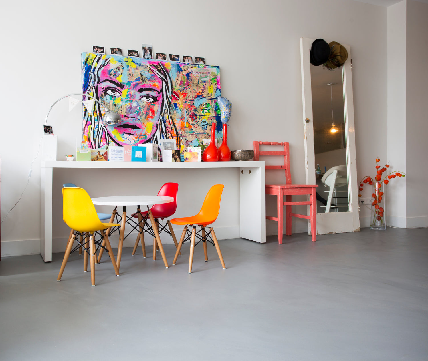 Modern interior with colorful chairs and a large abstract painting on a white wall.