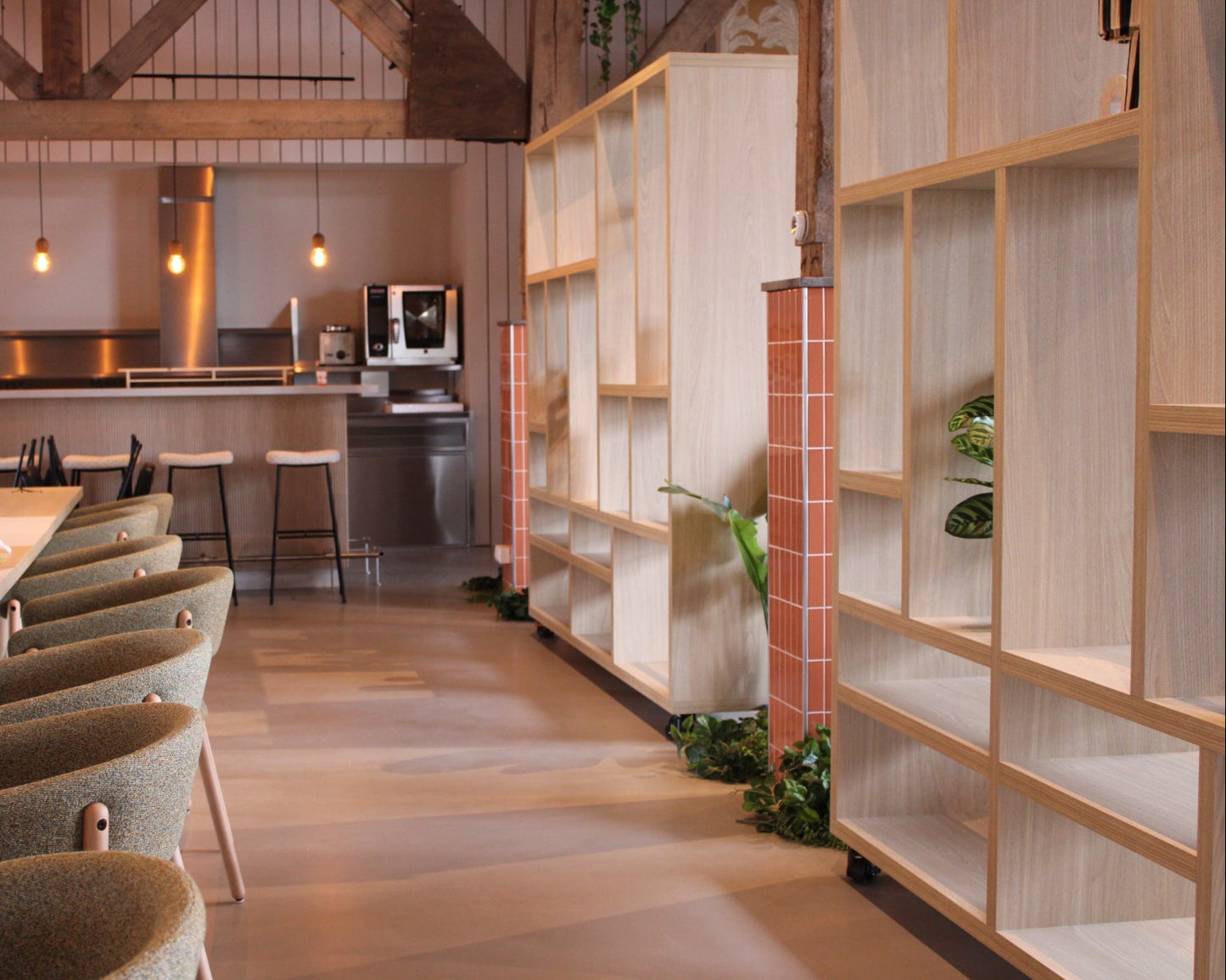Modern restaurant interior with wooden chairs, tables, and a kitchen in the background.